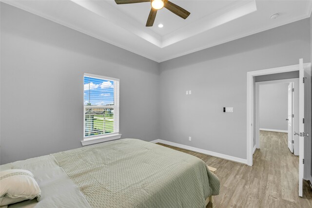 bedroom featuring ornamental molding, a tray ceiling, ceiling fan, and light hardwood / wood-style floors