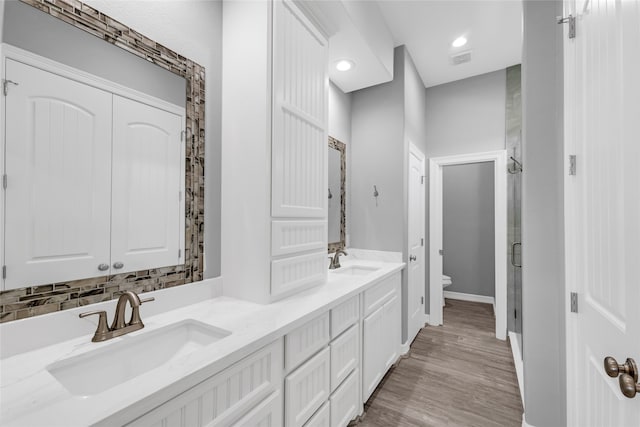 bathroom featuring vanity, backsplash, hardwood / wood-style flooring, toilet, and an enclosed shower