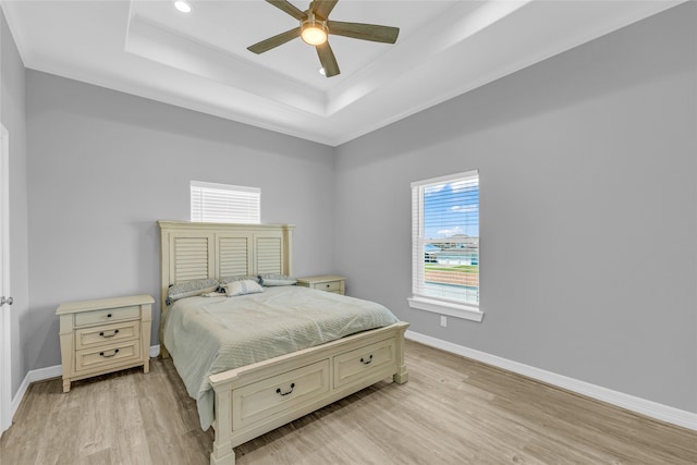 bedroom featuring multiple windows, a tray ceiling, and ceiling fan