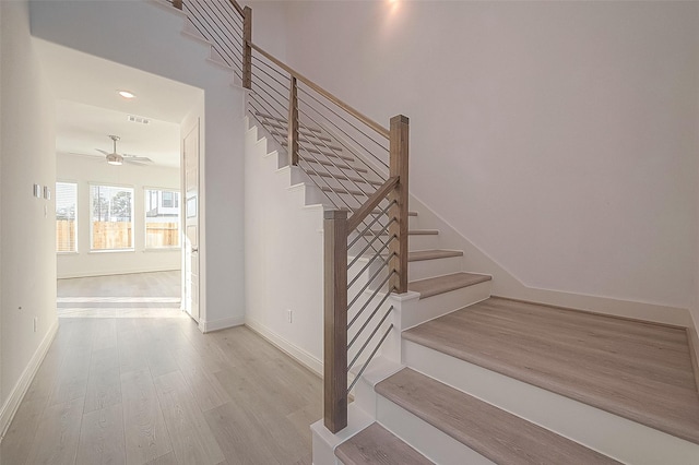 stairs with ceiling fan and hardwood / wood-style flooring