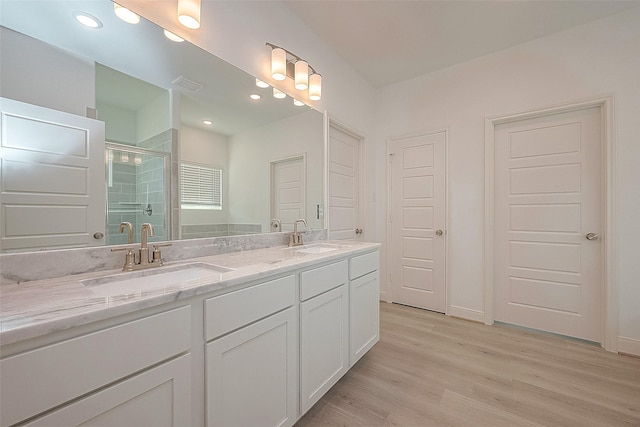 bathroom with hardwood / wood-style flooring, vanity, and a shower with door