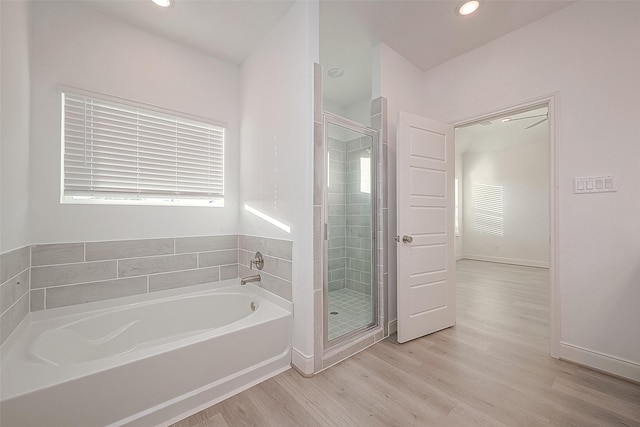 bathroom with hardwood / wood-style flooring and shower with separate bathtub