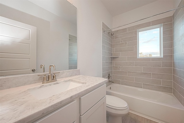 full bathroom featuring hardwood / wood-style flooring, vanity, tiled shower / bath combo, and toilet