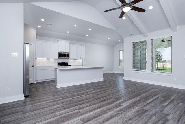 kitchen featuring dark wood-type flooring, vaulted ceiling with beams, an island with sink, stainless steel appliances, and white cabinets