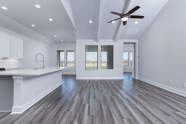 unfurnished living room featuring lofted ceiling with beams, dark hardwood / wood-style flooring, sink, and ceiling fan