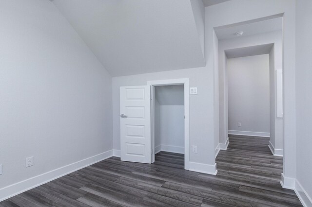 unfurnished bedroom featuring lofted ceiling, dark wood-type flooring, and a closet