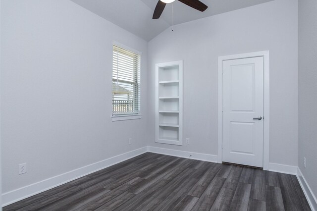 unfurnished room with vaulted ceiling, dark hardwood / wood-style floors, ceiling fan, and built in shelves