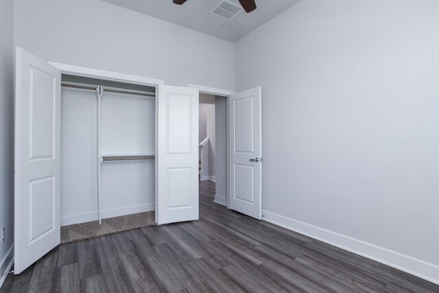 unfurnished bedroom featuring dark wood-type flooring, ceiling fan, and a closet