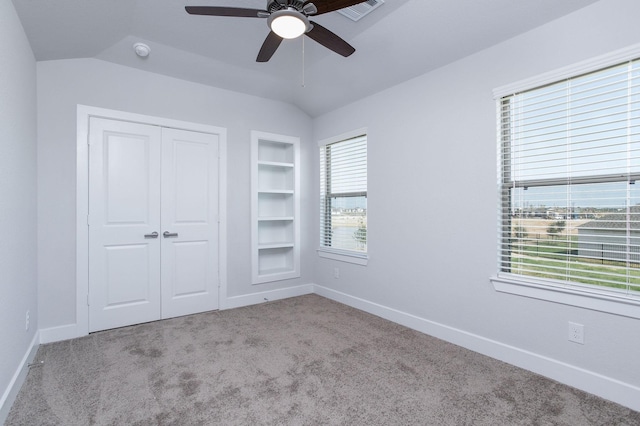 unfurnished bedroom with vaulted ceiling, light colored carpet, ceiling fan, and a closet