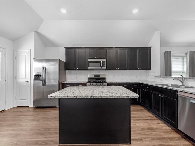 kitchen featuring a center island, light stone countertops, backsplash, and appliances with stainless steel finishes