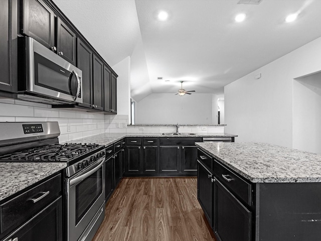 kitchen with stainless steel appliances, vaulted ceiling, ceiling fan, sink, and a center island