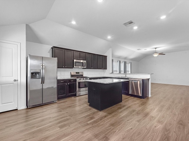 kitchen with backsplash, stainless steel appliances, vaulted ceiling, ceiling fan, and a center island