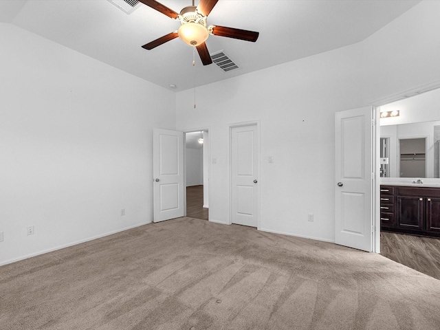 unfurnished bedroom featuring ensuite bathroom, ceiling fan, light colored carpet, and sink