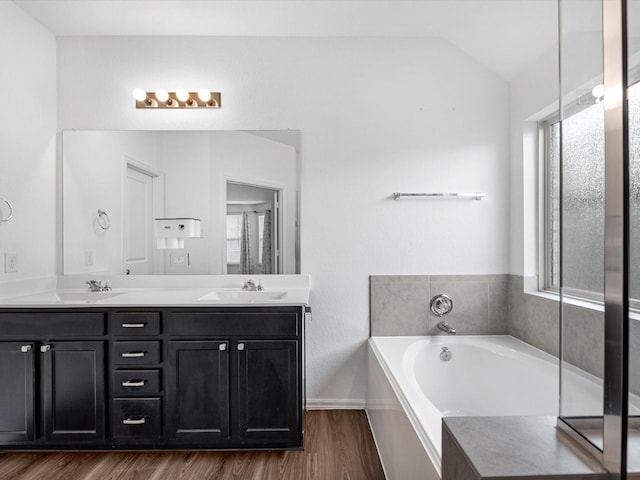 bathroom with a bathtub, vanity, lofted ceiling, and hardwood / wood-style flooring