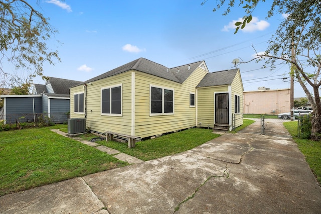 rear view of property with a lawn and cooling unit