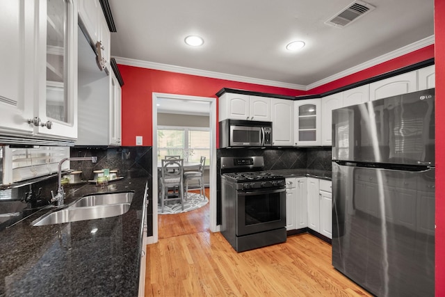 kitchen featuring appliances with stainless steel finishes, tasteful backsplash, sink, light hardwood / wood-style flooring, and white cabinetry