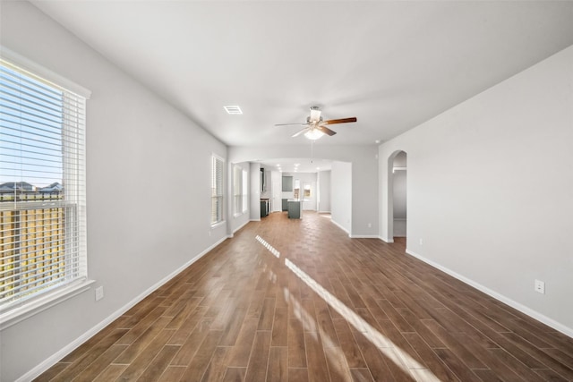 unfurnished living room with dark hardwood / wood-style flooring, ceiling fan, and a healthy amount of sunlight