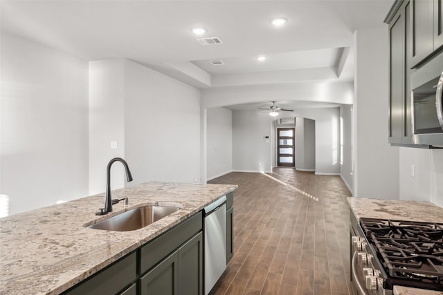 kitchen with ceiling fan, sink, stainless steel appliances, light stone counters, and gray cabinets