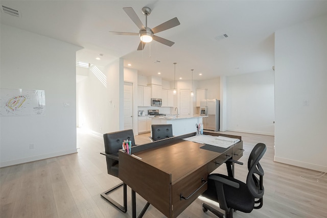 office area with ceiling fan, sink, and light wood-type flooring