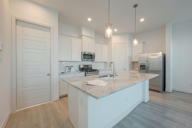 kitchen with white cabinets, sink, stainless steel appliances, and an island with sink