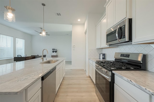 kitchen with white cabinets, pendant lighting, sink, and stainless steel appliances