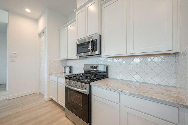 kitchen featuring decorative backsplash, appliances with stainless steel finishes, light stone counters, light hardwood / wood-style floors, and white cabinetry