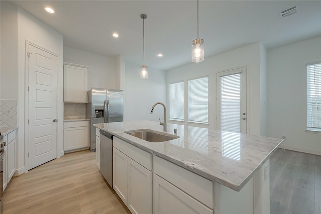 kitchen featuring decorative backsplash, appliances with stainless steel finishes, sink, a center island with sink, and hanging light fixtures