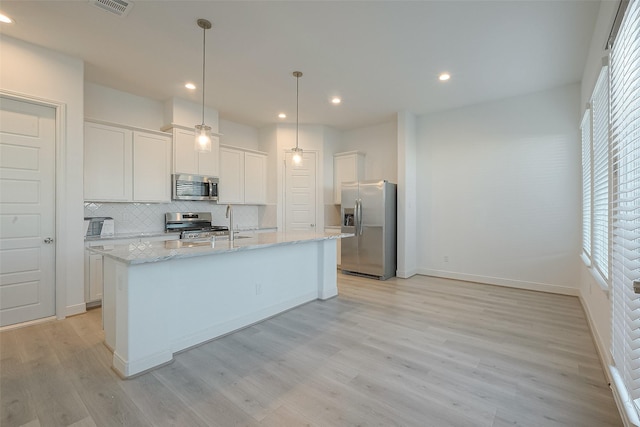 kitchen with light hardwood / wood-style flooring, an island with sink, decorative light fixtures, white cabinetry, and stainless steel appliances