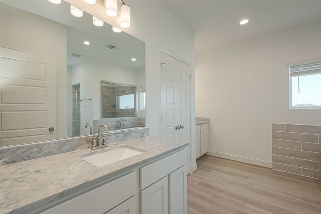 bathroom featuring vanity, a tile shower, and wood-type flooring