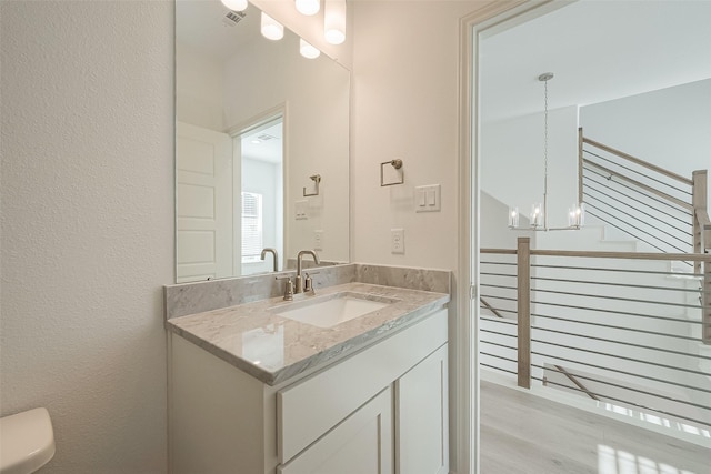 bathroom featuring a notable chandelier, vanity, and toilet