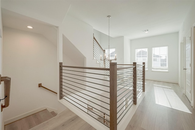 staircase with hardwood / wood-style flooring and a notable chandelier