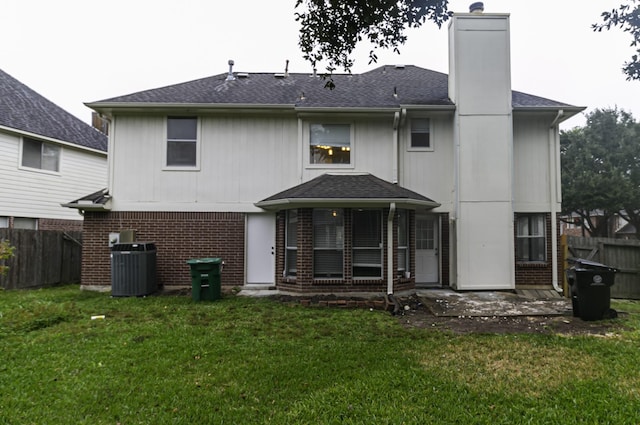 rear view of house with central AC and a yard