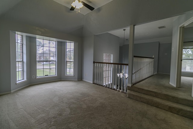 carpeted empty room with ceiling fan, plenty of natural light, and vaulted ceiling