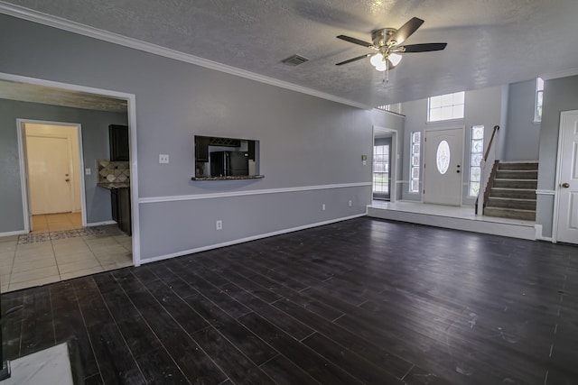 unfurnished living room with a textured ceiling, ceiling fan, dark hardwood / wood-style floors, and crown molding