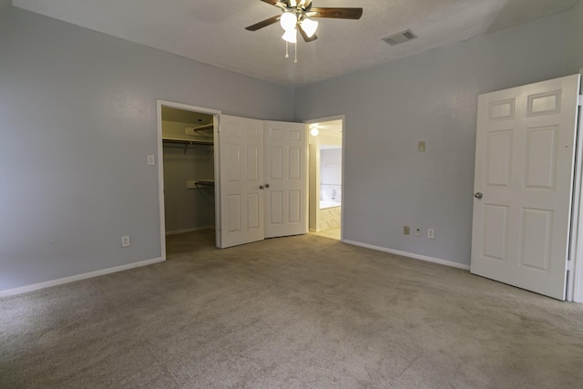 unfurnished bedroom with a closet, light colored carpet, a spacious closet, and ceiling fan