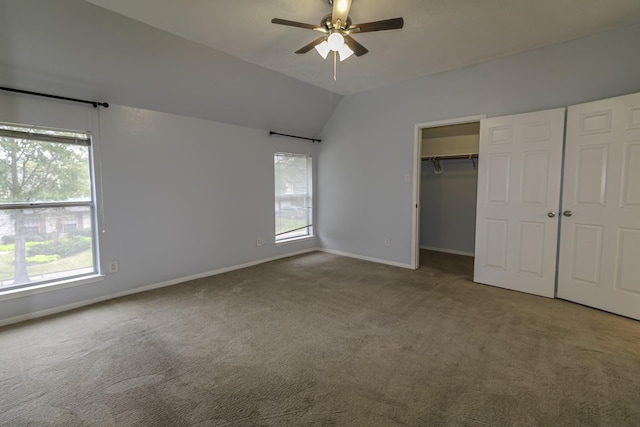 unfurnished bedroom with carpet, ceiling fan, a spacious closet, and vaulted ceiling