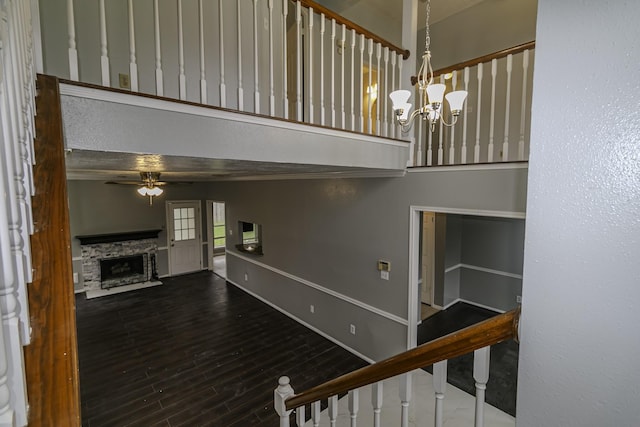 stairway with hardwood / wood-style floors, ceiling fan with notable chandelier, and a fireplace