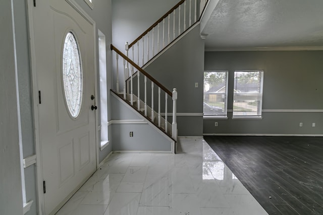 entrance foyer with a textured ceiling and ornamental molding