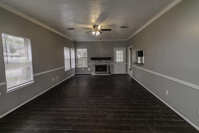 unfurnished living room featuring ceiling fan, dark hardwood / wood-style floors, ornamental molding, a textured ceiling, and a fireplace