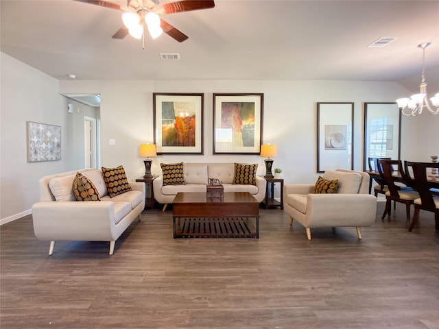 living room featuring ceiling fan with notable chandelier and dark wood-type flooring