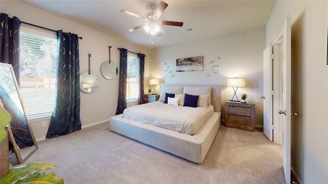 bedroom with ceiling fan, light colored carpet, and multiple windows