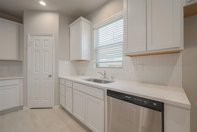 kitchen featuring white cabinets, sink, stainless steel dishwasher, tasteful backsplash, and light stone counters