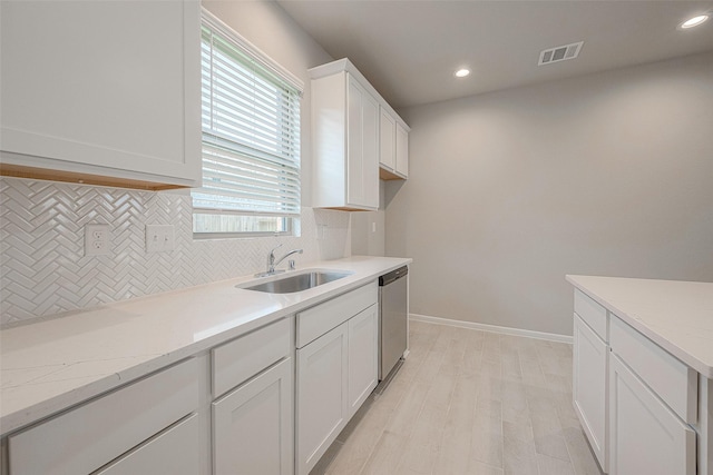 kitchen with white cabinetry, dishwasher, sink, light stone counters, and decorative backsplash