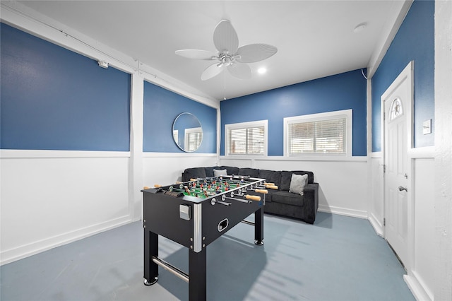 recreation room with ceiling fan and concrete flooring