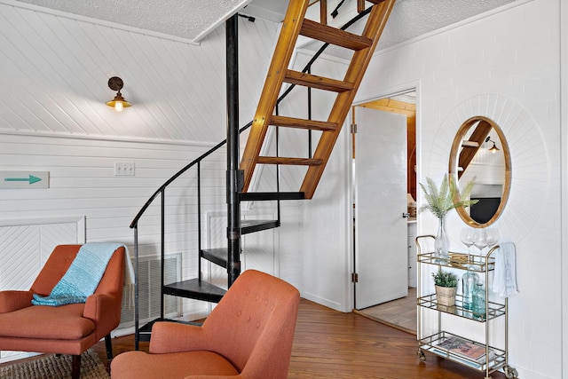 stairs featuring hardwood / wood-style floors, wood walls, and a textured ceiling