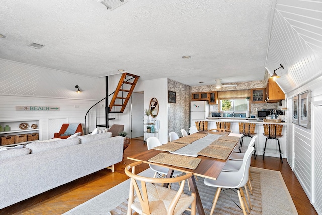 dining area with built in shelves, a textured ceiling, and light hardwood / wood-style floors