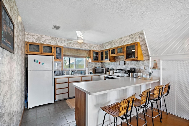 kitchen with ceiling fan, a kitchen breakfast bar, tile patterned floors, kitchen peninsula, and appliances with stainless steel finishes