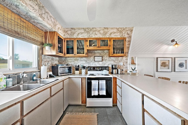 kitchen with dark tile patterned flooring, white electric range, sink, and a textured ceiling