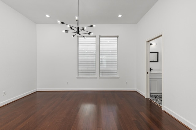 unfurnished room featuring dark hardwood / wood-style flooring and a notable chandelier