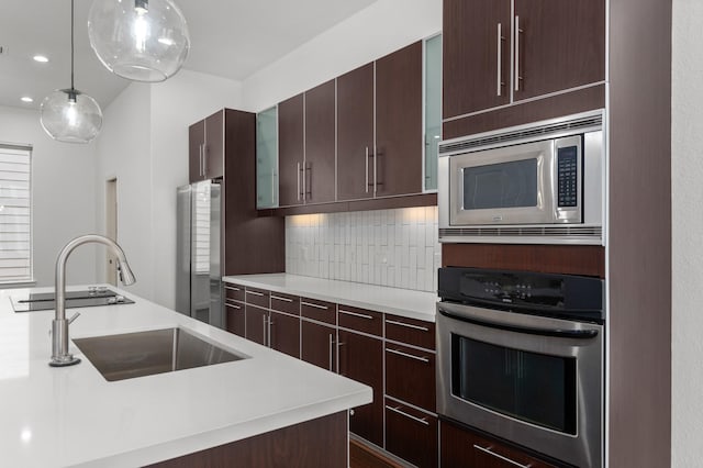 kitchen featuring decorative backsplash, stainless steel appliances, sink, a kitchen island, and hanging light fixtures